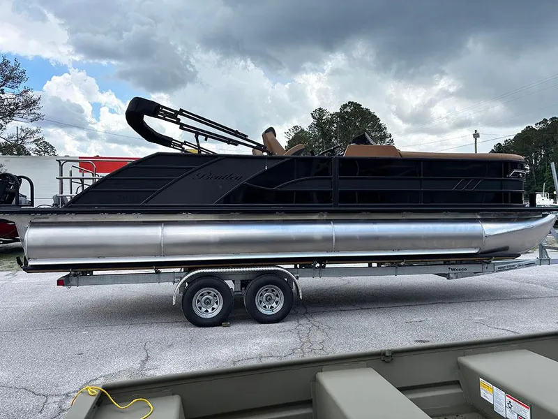 Slide: The Image of 2025 Bentley Pontoons Elite 253 Swingback Dual Captain Full Tritoon on trailer, under cloudy sky. - 5