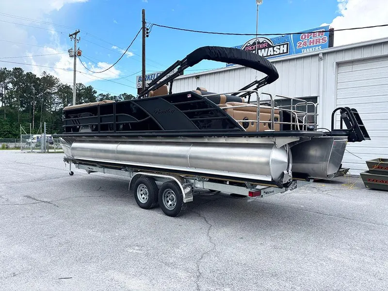 Slide: The Image of 2025 Bentley Pontoons Elite 253 Swingback Dual Captain Full Tritoon on trailer, parked outdoors. - 8