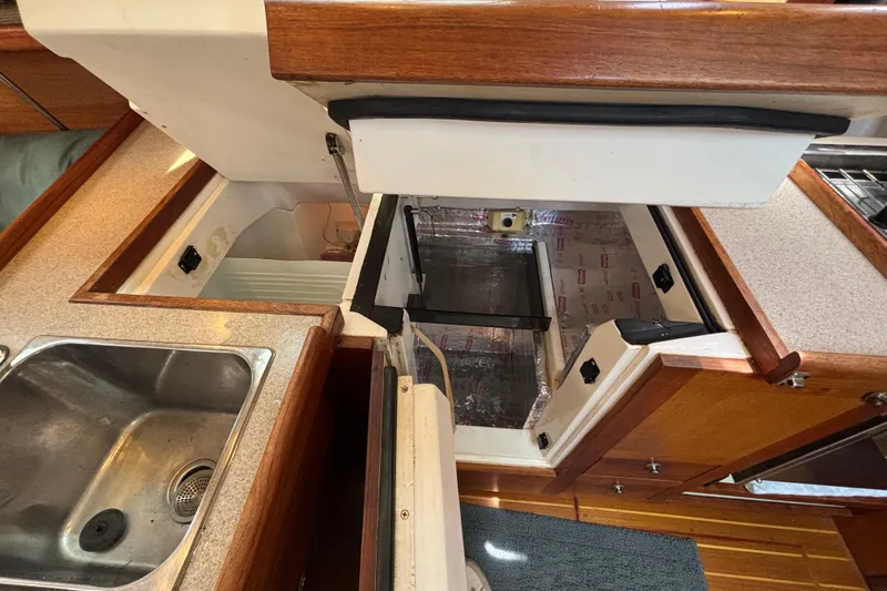 Slide: The Image of Interior of a 1999 Hunter 410 yacht kitchen with open storage compartments. - 40