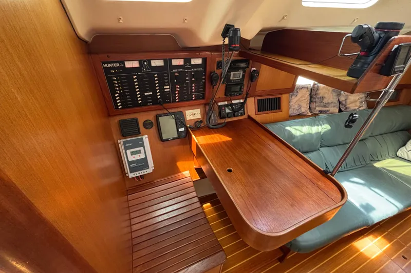 Slide: The Image of Navigation station of 1999 Hunter 410 sailboat with control panels and seating area. - 43