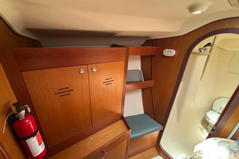 Slide: The Image of 1999 Hunter 410 yacht interior with wooden cabinets, fire extinguisher, and compact bathroom. - 48