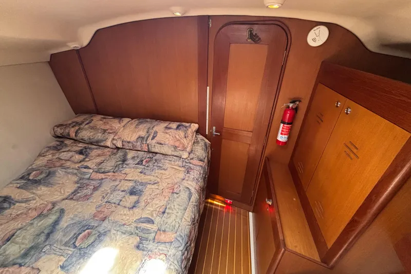 Slide: The Image of Cozy cabin interior of 1999 Hunter 410 sailboat with bed, wooden cabinetry, and fire extinguisher. - 49