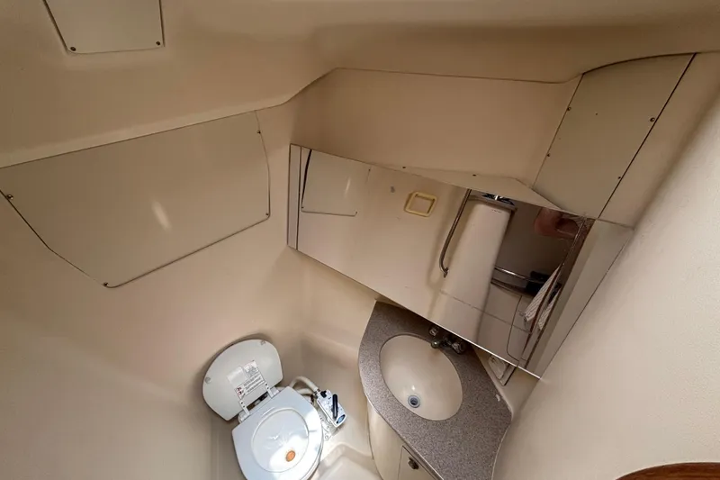 Slide: The Image of Compact bathroom in a 1999 Hunter 410 yacht, featuring a toilet, sink, and mirror. - 52