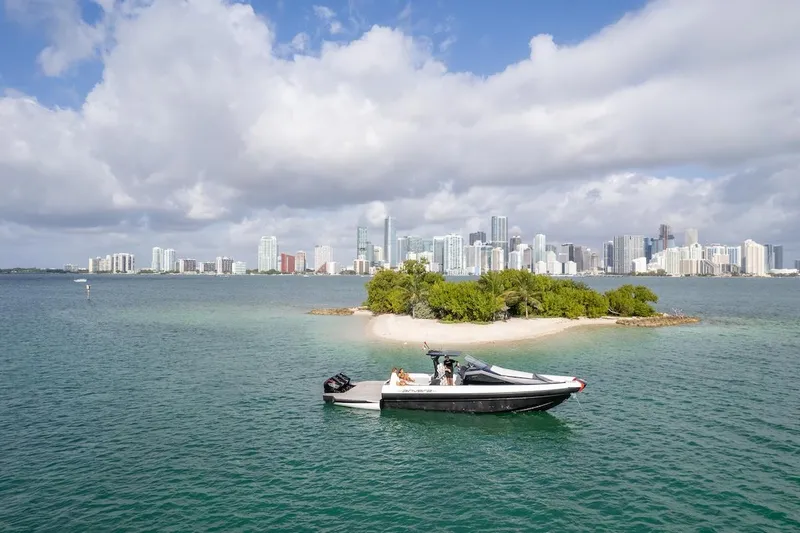 Slide: The Image of 2025 Anvera 42 Speedster boat cruising near a small island with city skyline backdrop. - 22