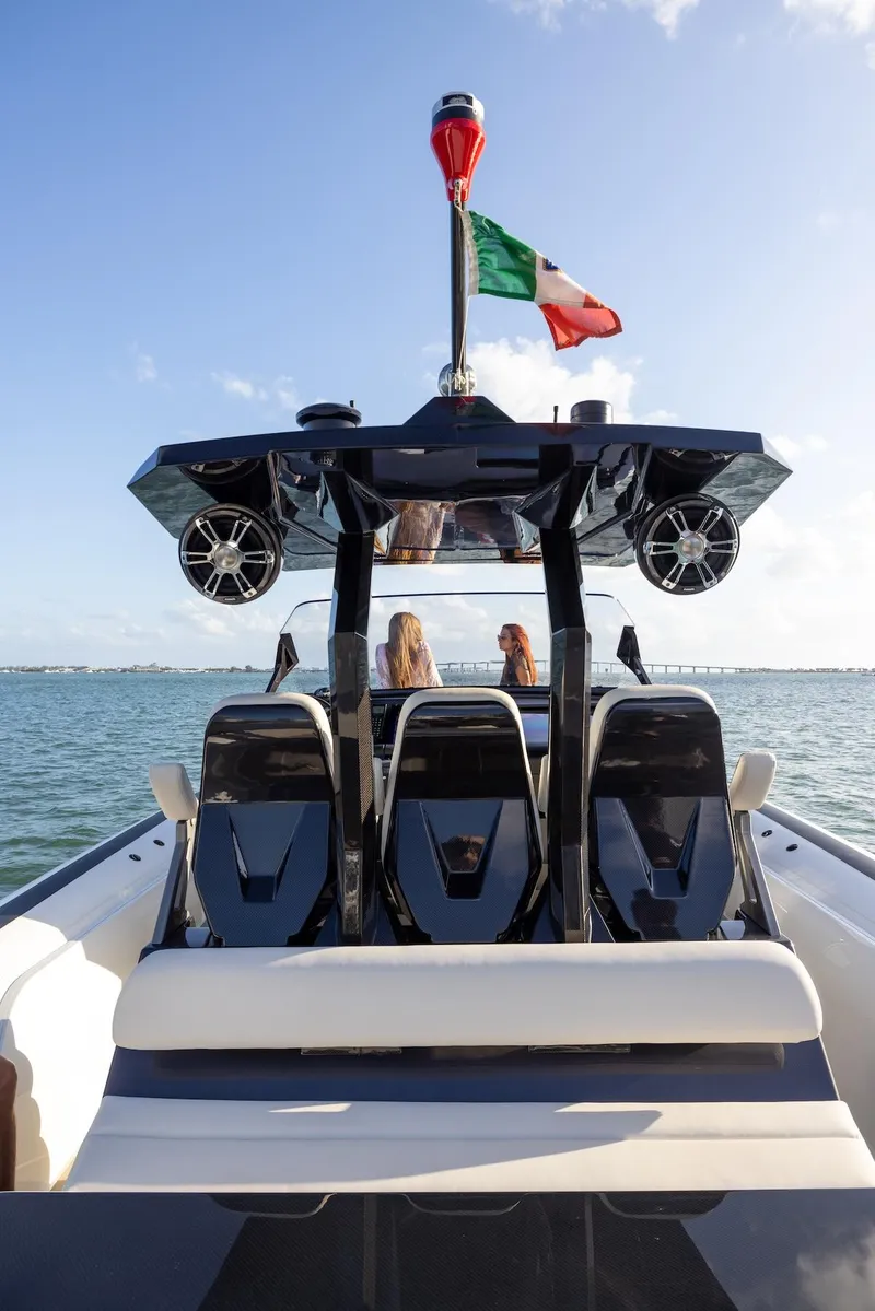 Slide: The Image of 2025 Anvera 42 Speedster boat on water, rear view with flag and passengers. - 6