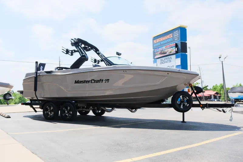 Slide: The Image of 2025 MasterCraft XT24 boat on trailer in parking lot, sunny day. - 12