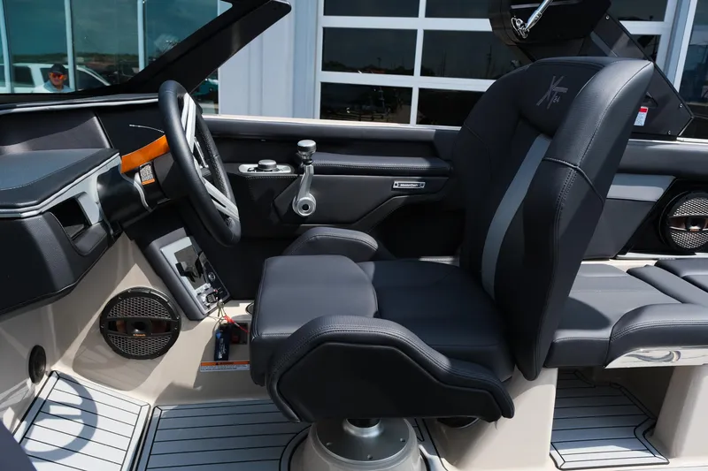 Slide: The Image of 2025 MasterCraft XT24 boat interior with sleek black seating and modern dashboard. - 23