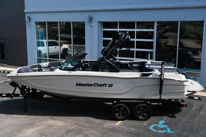 Slide: The Image of 2025 MasterCraft XT24 boat on trailer, parked outside a building. - 3