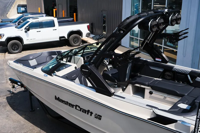 Slide: The Image of 2025 MasterCraft XT24 boat parked near white trucks, showcasing sleek design and modern features. - 4