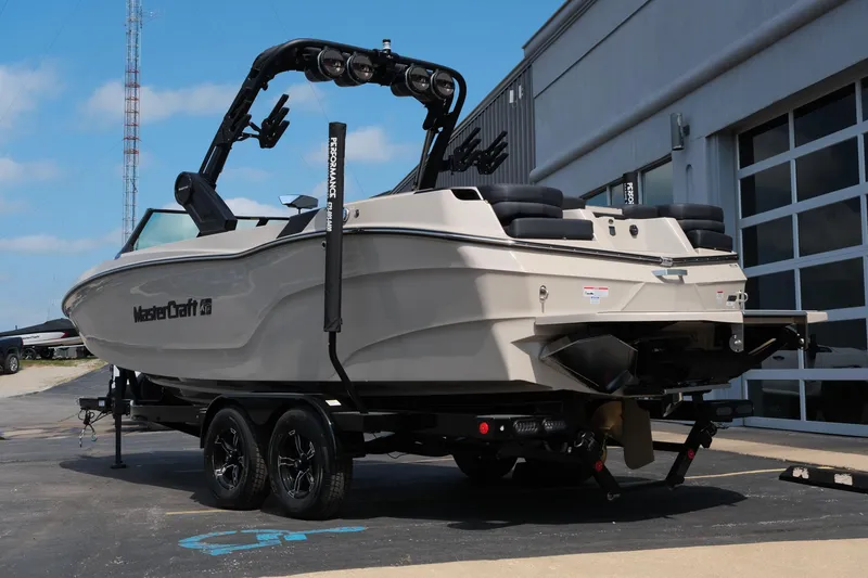 Slide: The Image of 2025 MasterCraft XT24 boat on trailer, parked outdoors near a building. - 7