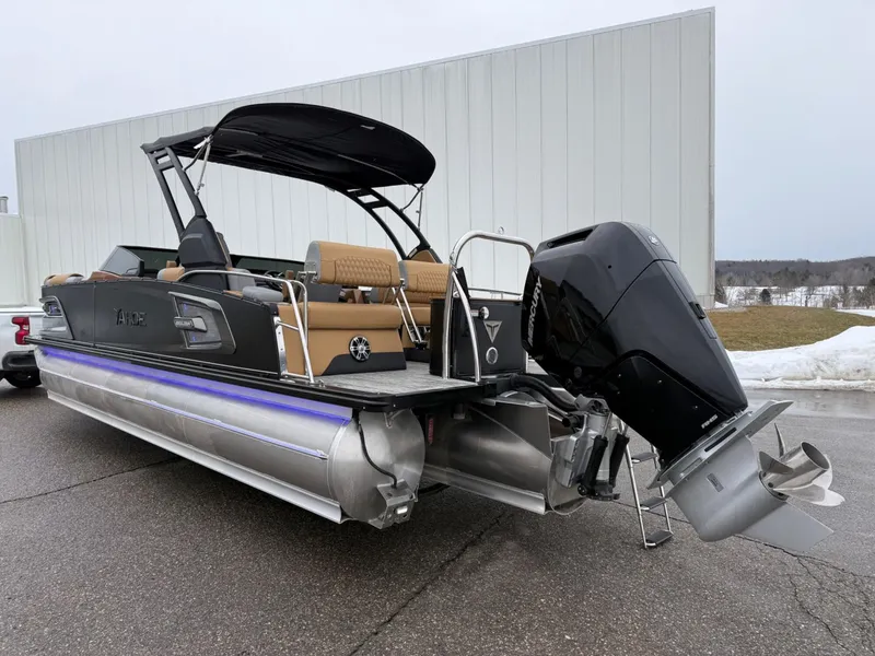 Slide: The Image of 2025 Tahoe Pontoon Grand Tahoe LTD Quad Lounge Windshield with outboard motor, parked outdoors. - 3