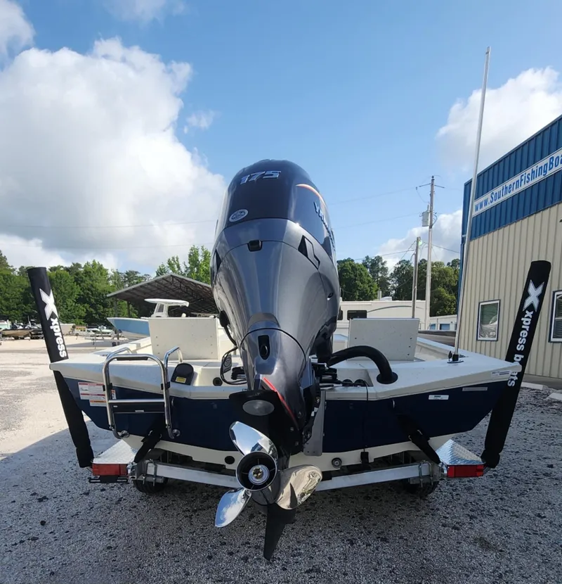 Slide: The Image of 2025 Xpress H22B boat with powerful outboard motor, parked outdoors near a building. - 1