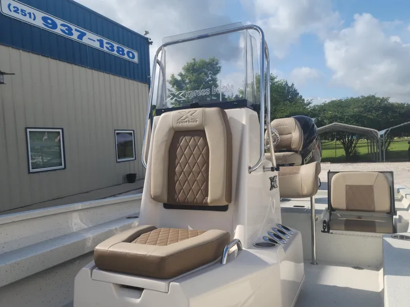 Slide: The Image of 2025 Xpress H22B boat interior with tan seating and console, parked outdoors. - 10