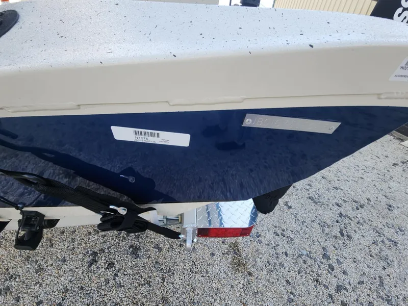 Slide: The Image of 2025 Xpress H22B boat trailer with blue and white hull, parked on gravel. - 12