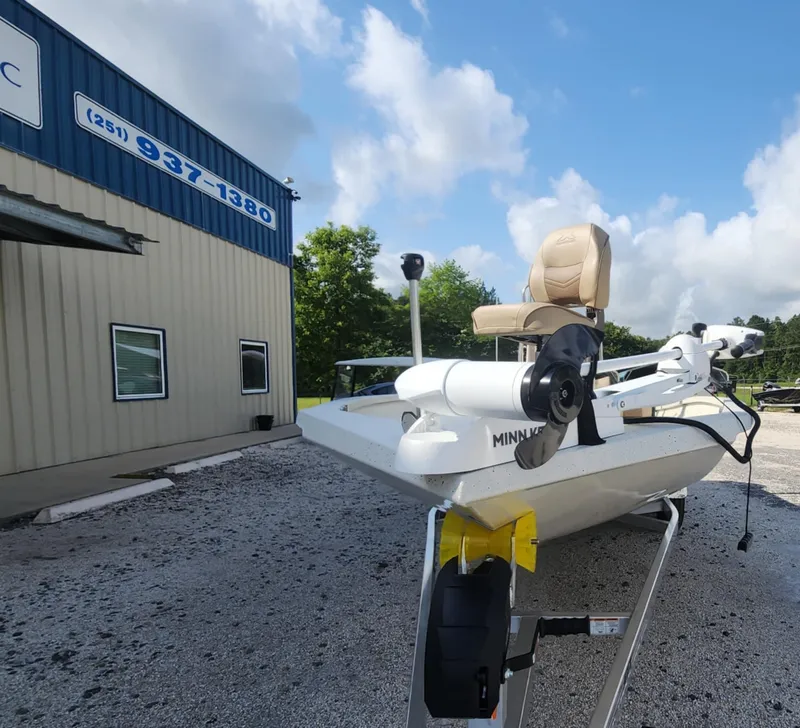 Slide: The Image of 2025 Xpress H22B boat with Minn Kota motor outside a building under a blue sky. - 2