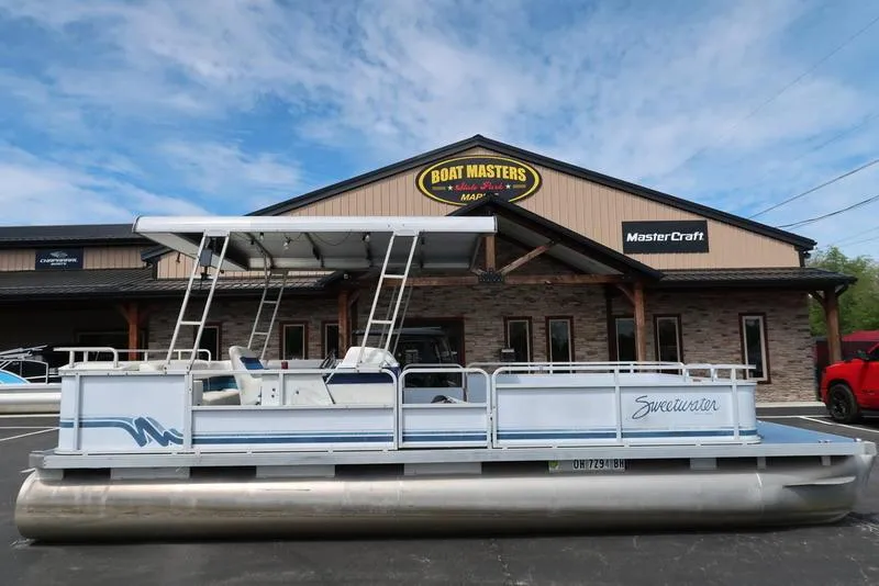 Slide: The Image of 1994 Sweetwater 2400 pontoon boat parked outside Boat Masters Marine store. - 1