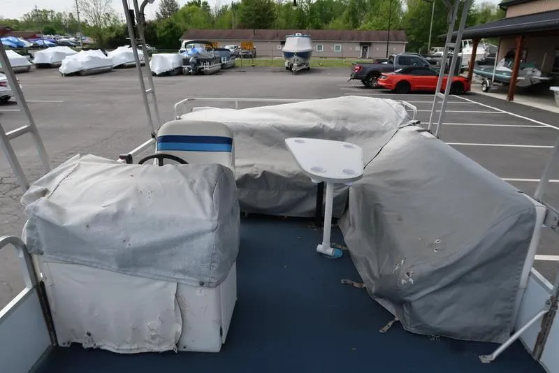 Slide: The Image of 1994 Sweetwater 2400 pontoon boat with covered seating and table in a parking lot. - 2