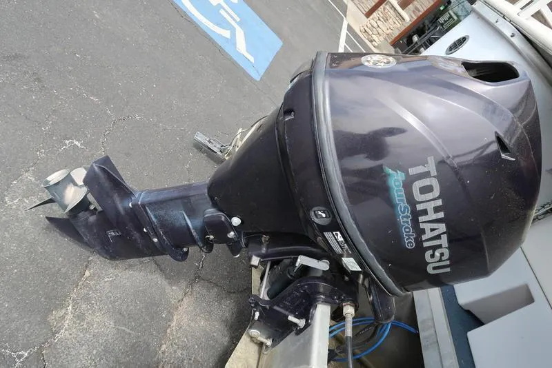Slide: The Image of Tohatsu outboard motor on a Sweetwater 2400, 1994 model, parked on asphalt. - 3