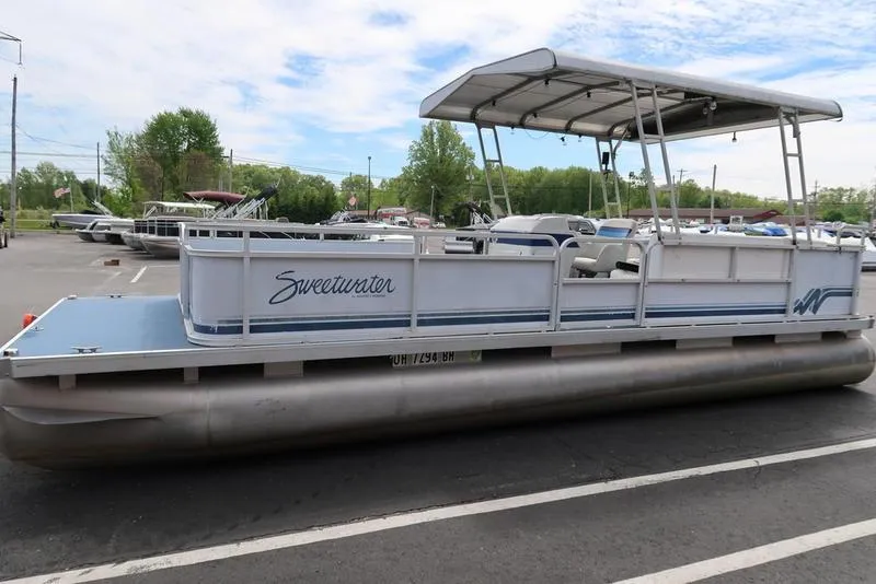 Slide: The Image of 1994 Sweetwater 2400 pontoon boat parked in a lot under a blue sky. - 5