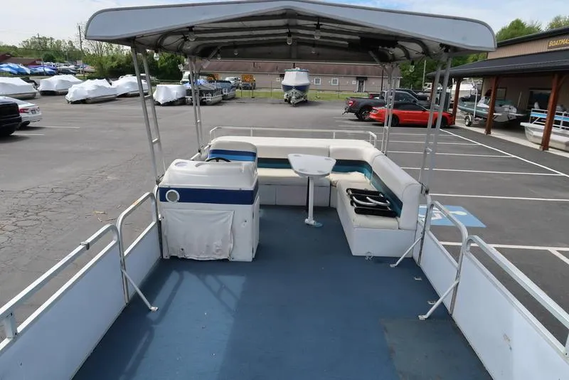 Slide: The Image of 1994 Sweetwater 2400 pontoon boat with canopy, spacious seating, and table in a parking lot. - 7
