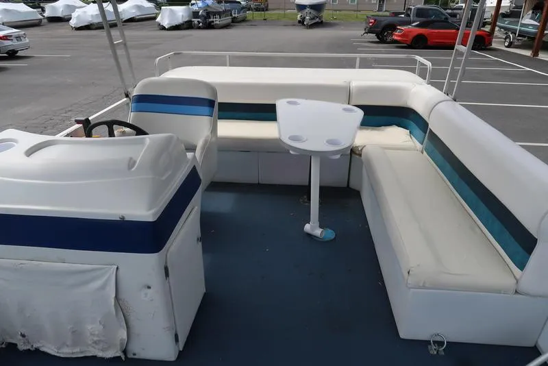 Slide: The Image of 1994 Sweetwater 2400 pontoon boat interior with seating and table in a parking lot. - 9