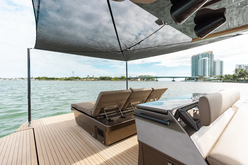 Slide: The Image of Luxury Anvera 48 yacht deck with sun loungers and canopy, overlooking serene waterfront view. - 12
