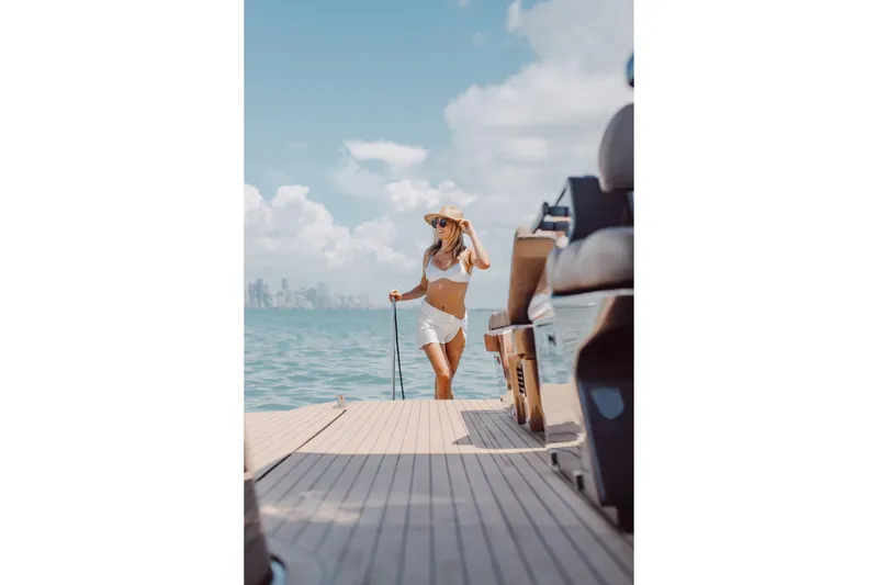 Slide: The Image of Woman enjoying sunny day on Anvera 48 yacht, 2025 model, with city skyline in background. - 49