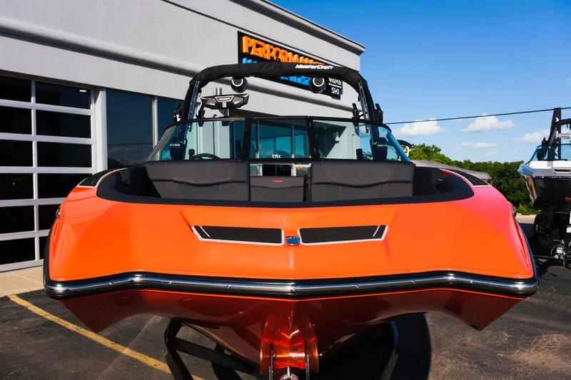 Slide: The Image of 2025 MasterCraft NXT24 boat in vibrant orange, parked outside a dealership. - 10