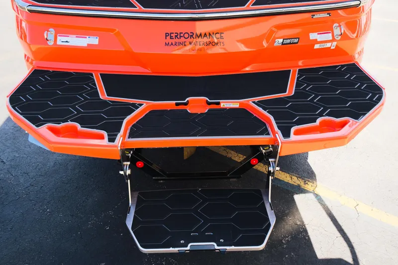 Slide: The Image of 2025 MasterCraft NXT24 boat with orange exterior and black deck, featuring a foldable swim platform. - 12