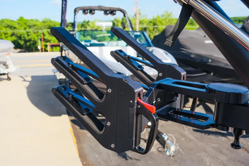 Slide: The Image of 2025 MasterCraft NXT24 boat with wakeboard racks, parked outdoors on a sunny day. - 16