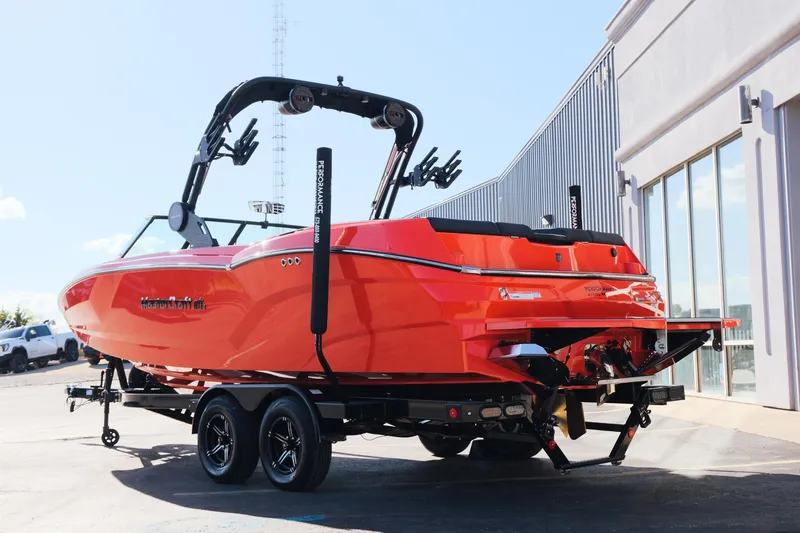 Slide: The Image of 2025 MasterCraft NXT24 boat in vibrant orange, parked on a trailer outside a building. - 5