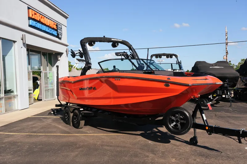 Slide: The Image of 2025 MasterCraft NXT24 boat in vibrant orange, parked outside a dealership. - 9