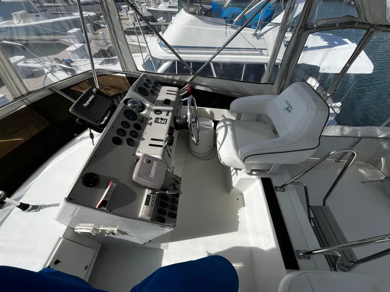 Slide: The Image of 1996 Carver 325 Aft Cabin helm with steering wheel and control panel, docked at marina. - 19