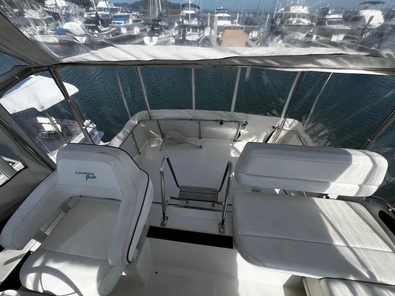 Slide: The Image of 1996 Carver 325 Aft Cabin yacht interior with white seating and marina view. - 21
