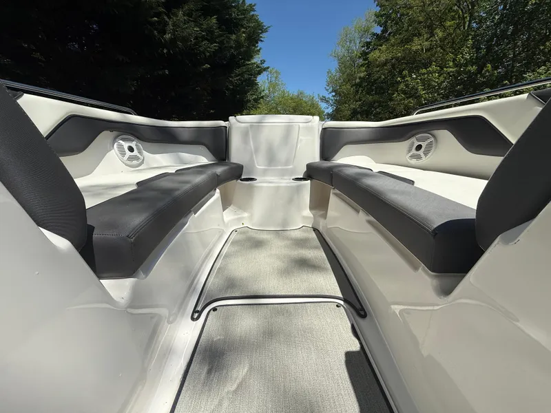 Slide: The Image of 2022 Yamaha AR210 boat interior with cushioned seating and speakers, surrounded by lush greenery. - 17