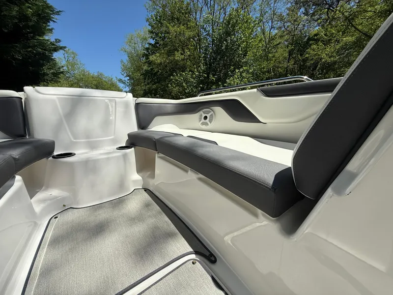 Slide: The Image of 2022 Yamaha AR210 boat interior with cushioned seating and speaker, surrounded by trees. - 19