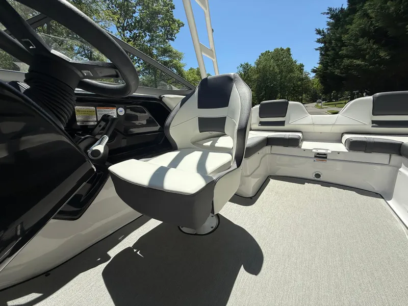 Slide: The Image of 2022 Yamaha AR210 boat interior with steering wheel and seating, surrounded by trees. - 27
