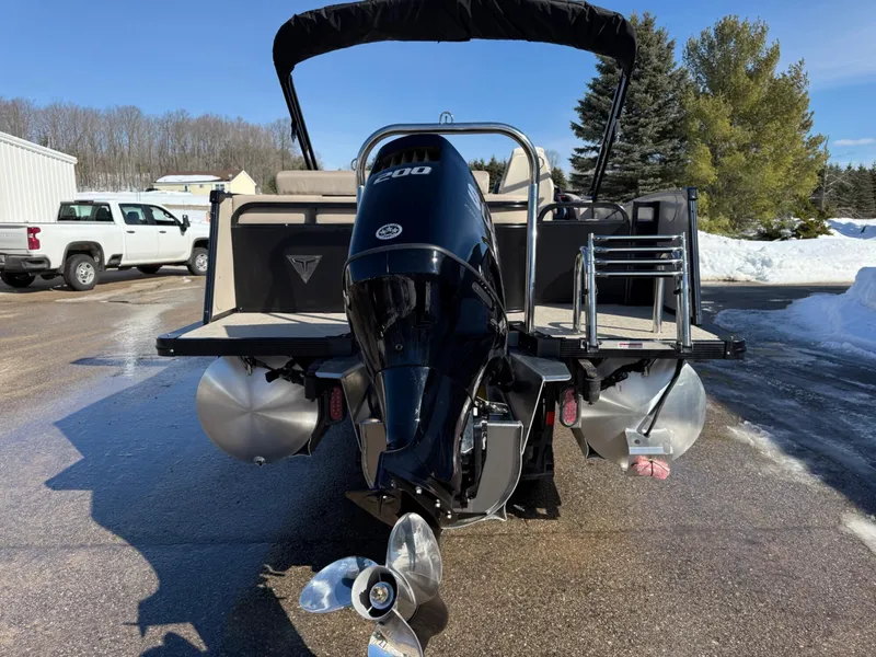 Slide: The Image of 2025 Tahoe Pontoon Cascade Versatile Rear Lounger with powerful outboard motor, parked outdoors. - 22