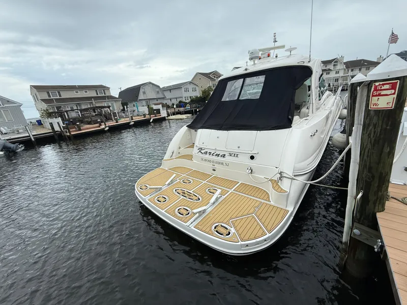 Slide: The Image of 2006 Sea Ray 52 Sundancer yacht docked at a marina, featuring a spacious deck. - 49