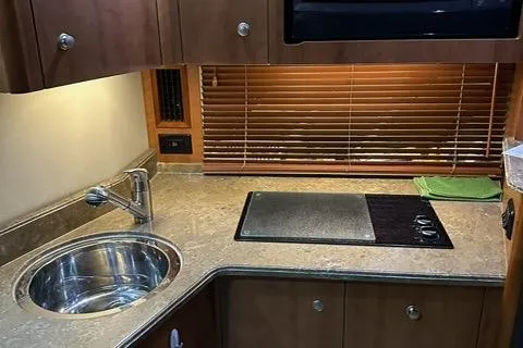 Slide: The Image of 2008 Cruisers Yachts 360 Express kitchen with sink, stovetop, and wooden cabinetry. - 15