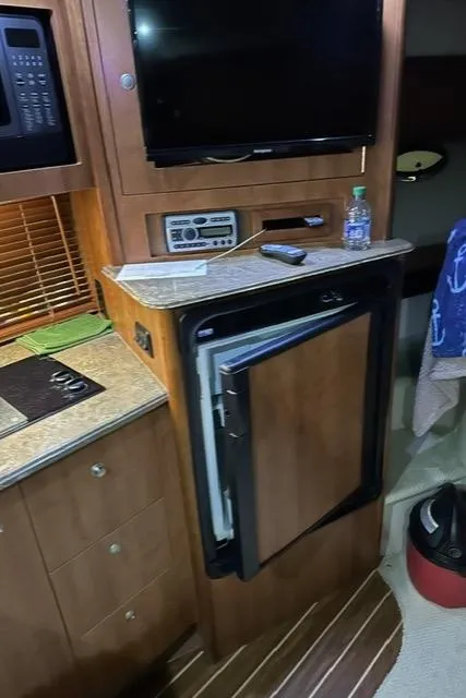 Slide: The Image of Interior of 2008 Cruisers Yachts 360 Express with fridge, TV, and wooden cabinetry. - 16