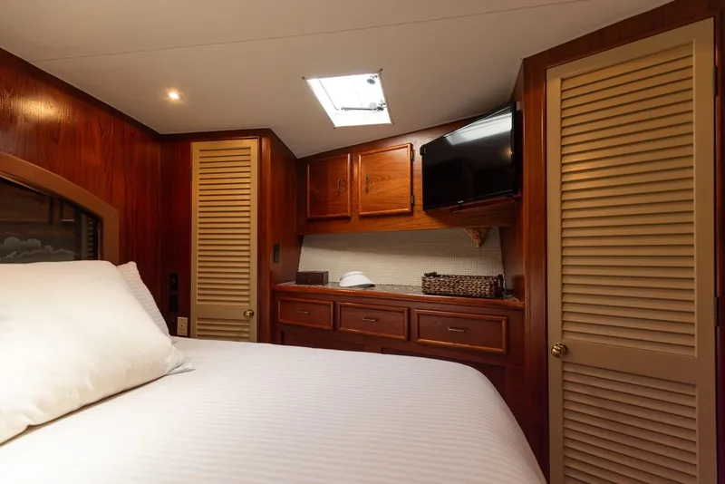 Slide: The Image of 1987 Ocean Yachts Convertible cabin with wood paneling, bed, TV, and storage cabinets. - 10