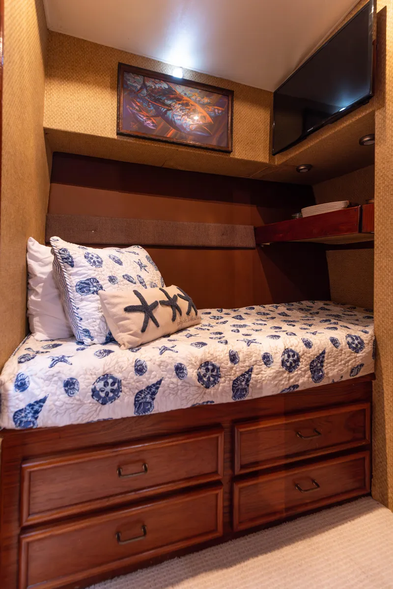 Slide: The Image of 1987 Ocean Yachts Convertible cabin with cozy bed, nautical decor, and wooden storage drawers. - 17