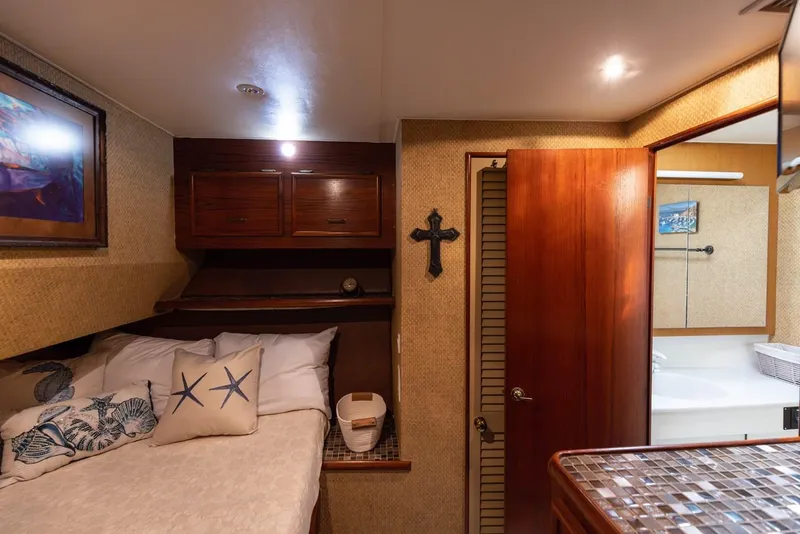 Slide: The Image of 1987 Ocean Yachts Convertible cabin interior with bed, wooden cabinets, and bathroom entrance. - 13
