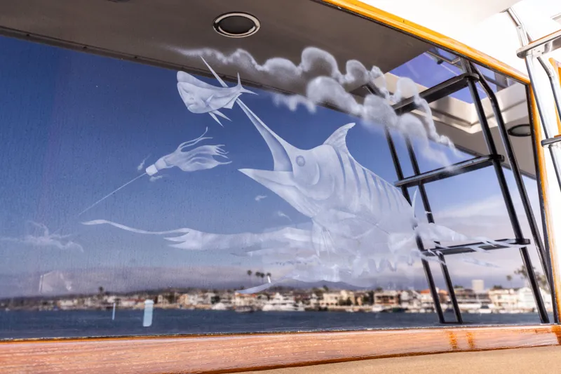 Slide: The Image of 1987 Ocean Yachts Convertible with marlin etching on window, reflecting coastal scenery. - 24