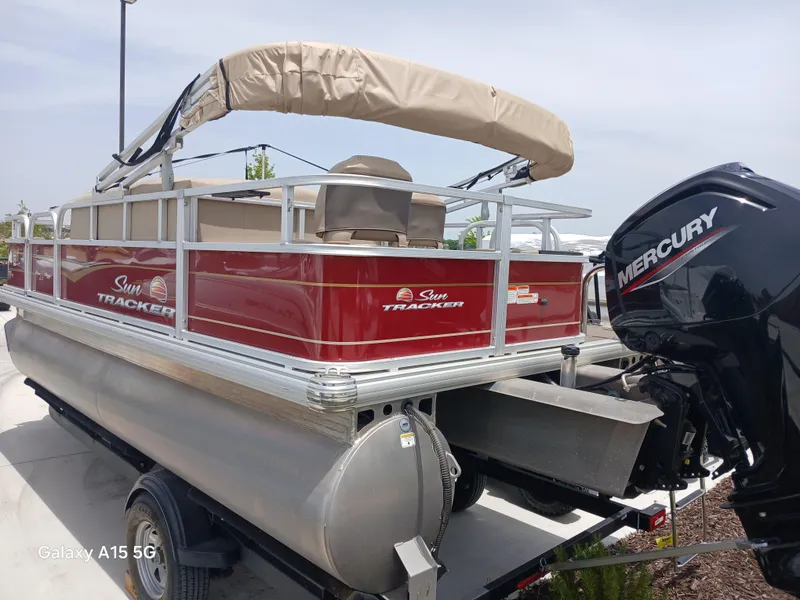 Slide: The Image of 2023 Sun Tracker 18BASSBUGGY pontoon boat with Mercury engine, red and beige design. - 2