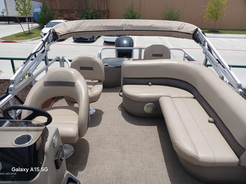 Slide: The Image of 2023 Sun Tracker 18BASSBUGGY pontoon boat with beige seating and canopy in a parking lot. - 4