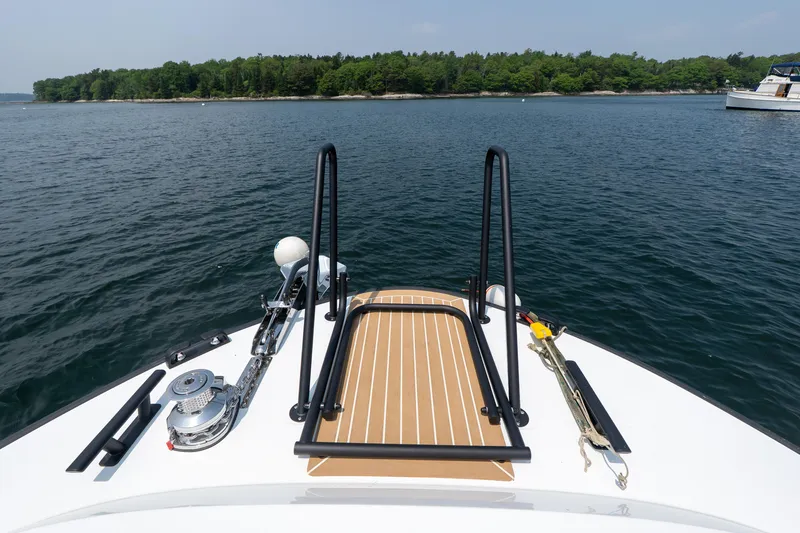 Slide: The Image of Targa 32 GT 2025 boat deck with railing, anchored on calm water near a forested shoreline. - 24