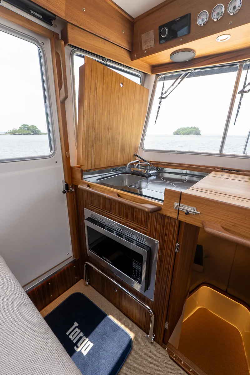 Slide: The Image of Interior of 2025 Targa 32 GT boat with wooden cabinetry and modern kitchen amenities. - 32