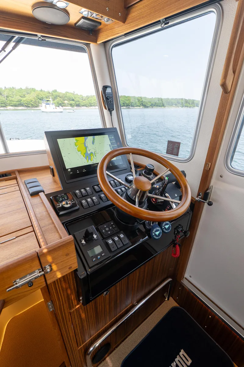 Slide: The Image of 2025 Targa 32 GT boat cockpit with wooden steering wheel and navigation screen. - 38